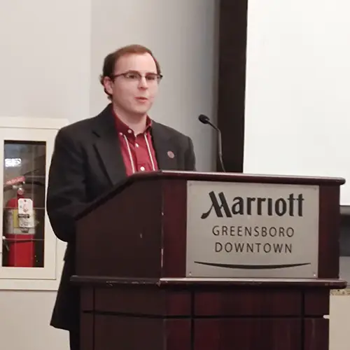 A man gives a presentation at a podium with Marriott branding on it