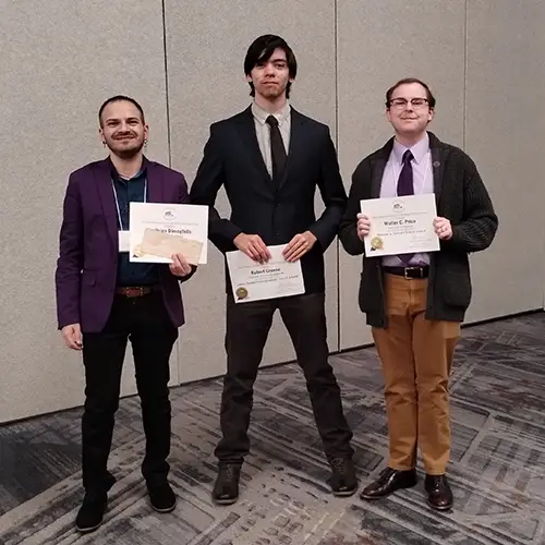 Three conference participants holding award plaques